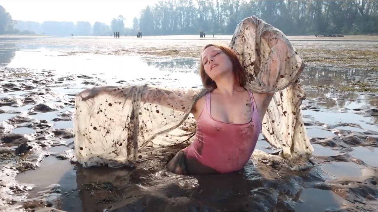 a woman with a scarf sitting in the mud