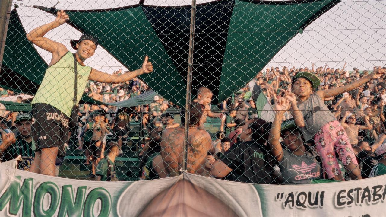 two kids clinging to a fence at a sports event