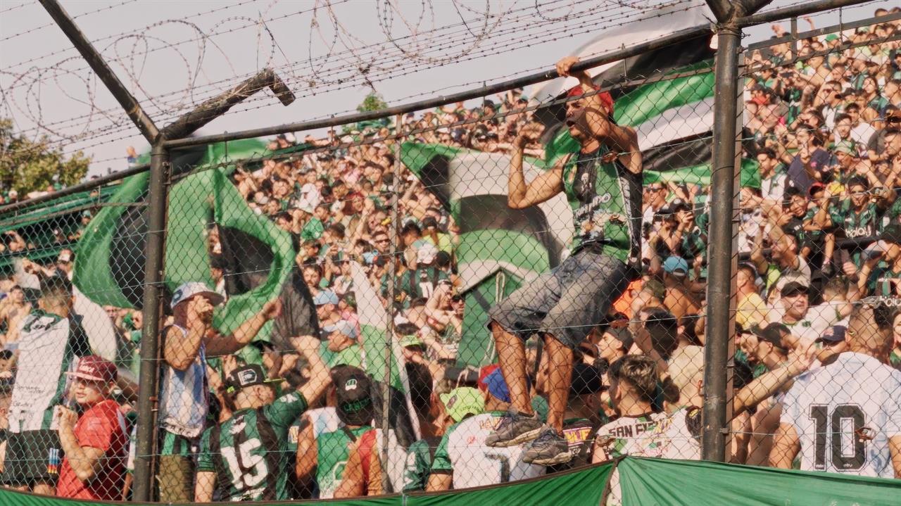 a person clinging to a fence in front of a crowd