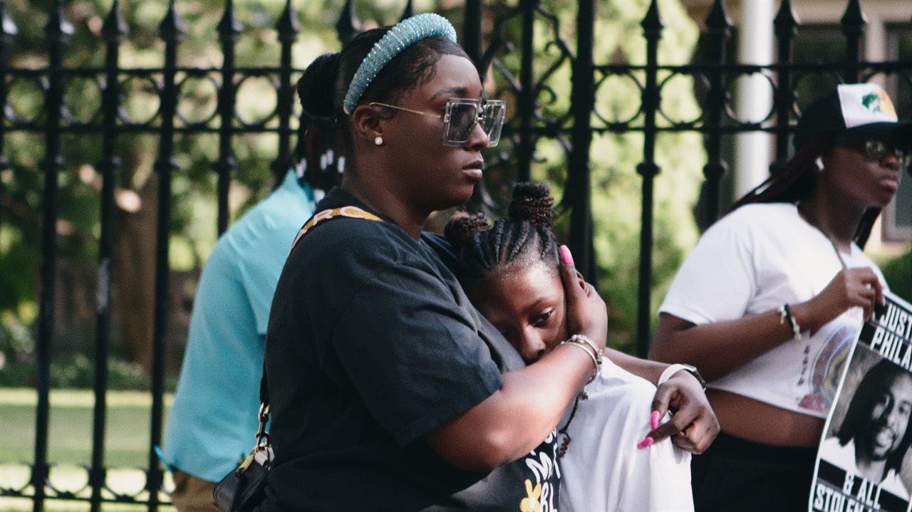 A Black woman hugging a child