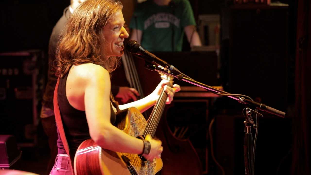 Ani DiFranco with a guitar and a microphone