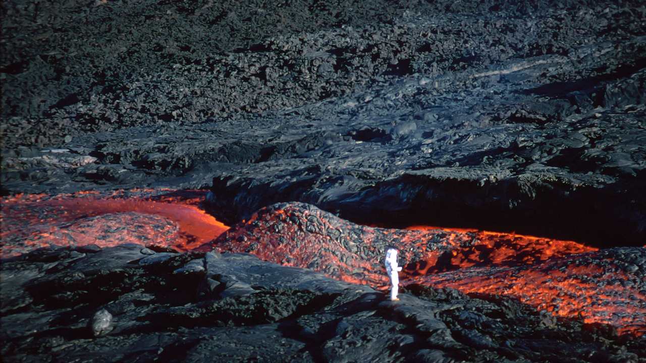 a person in a protective suit walking on a volcano