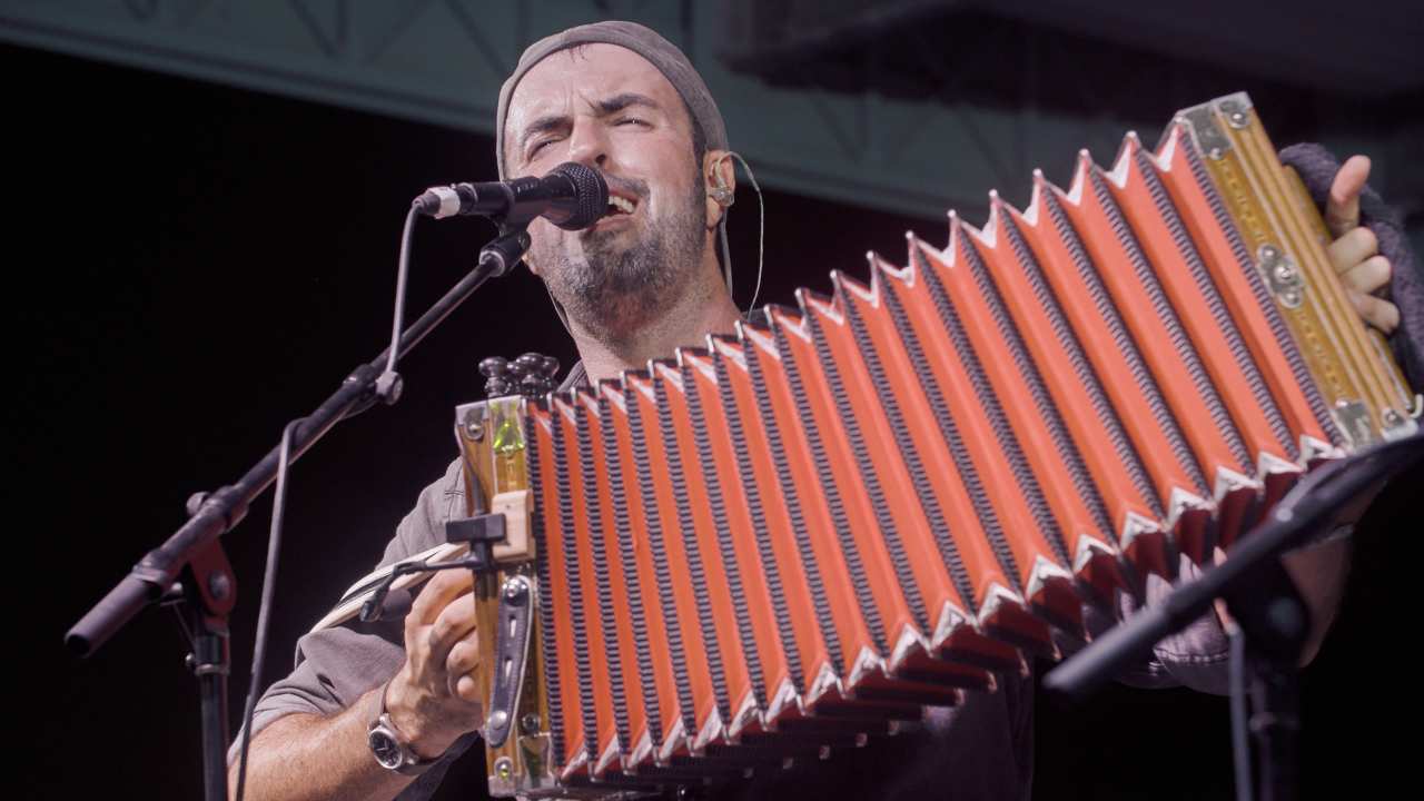 a man singing into a microphone with an accordian