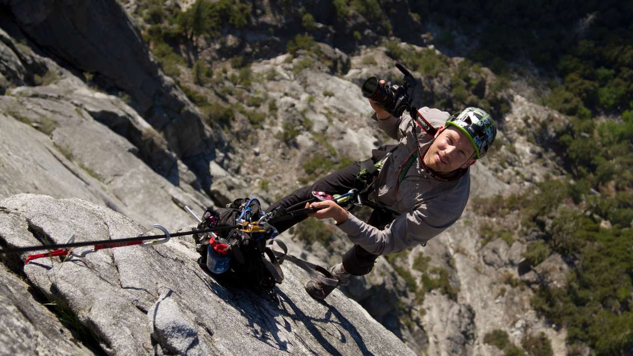 a man rockclimbing with a camera