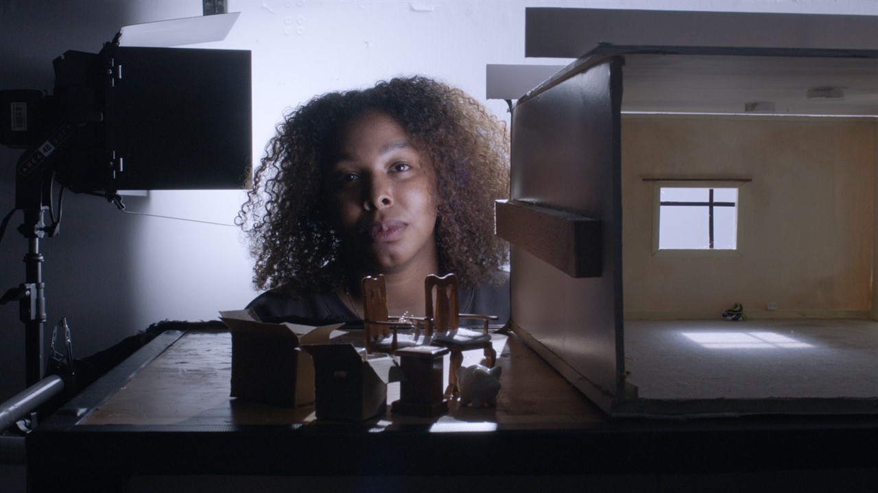 Woman's face beside an empty doll house