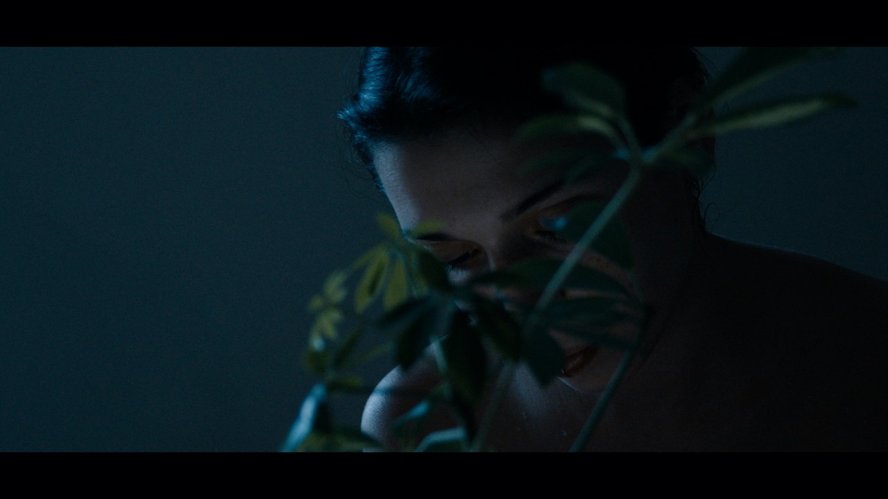 Closeup of a woman partially obscured by a plant