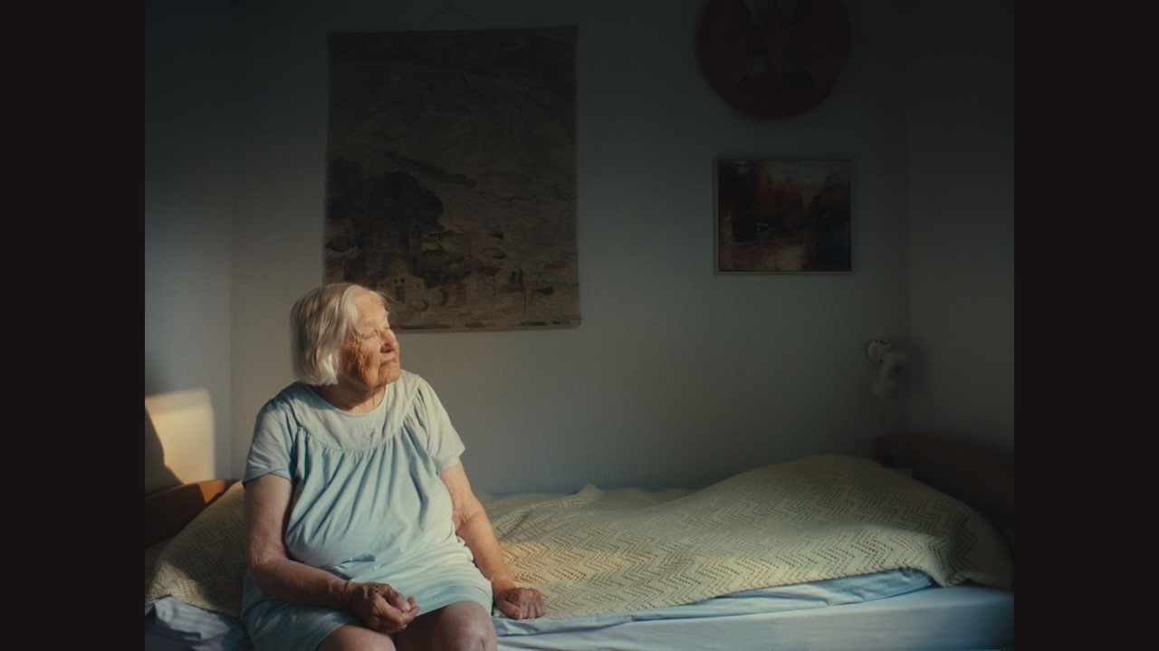 And elderly woman sits on a bed