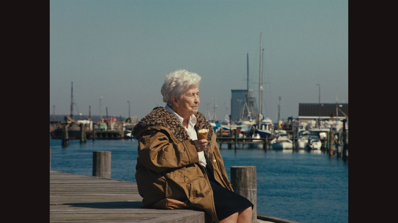 An elderly woman sits on a pier