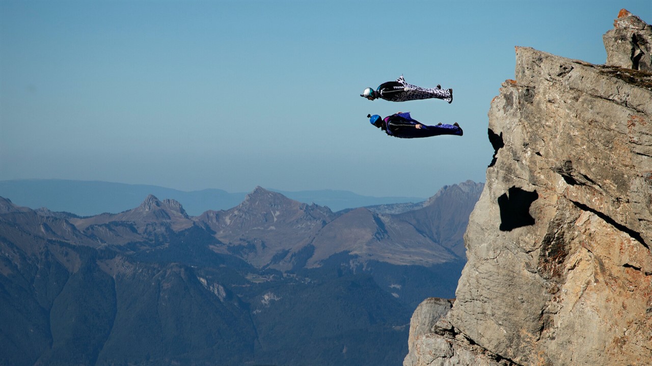 Two people base jumping off a cliff