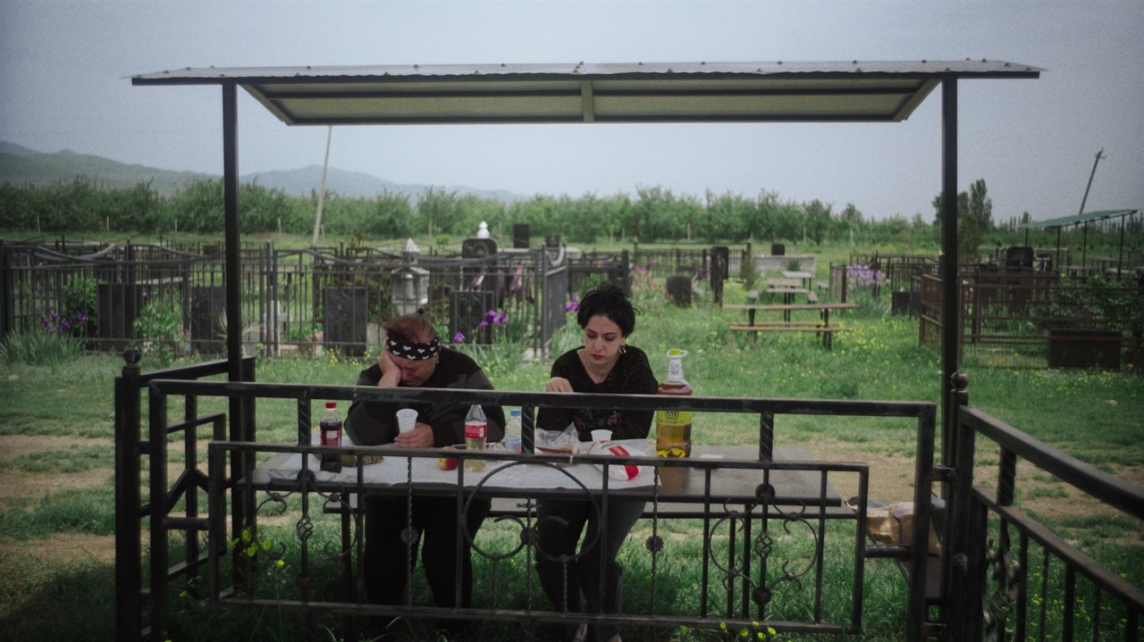 People sitting next to a graveyard eating