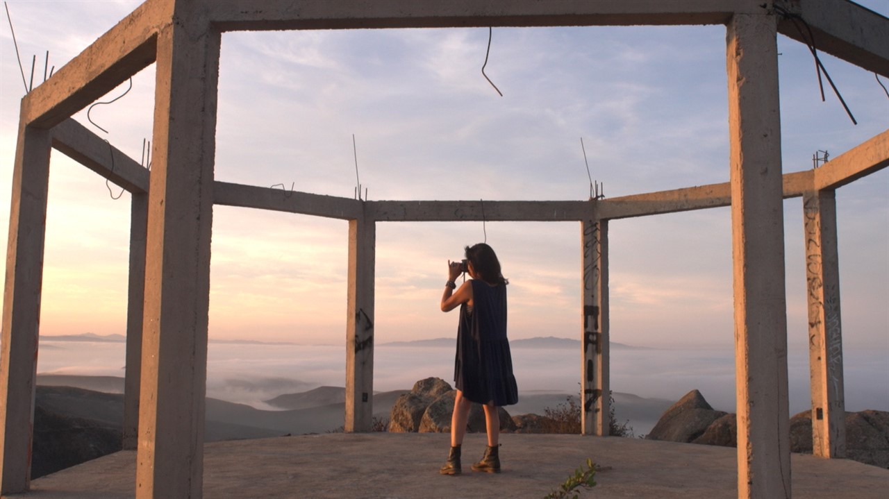 Woman staning on a lookout above the clouds