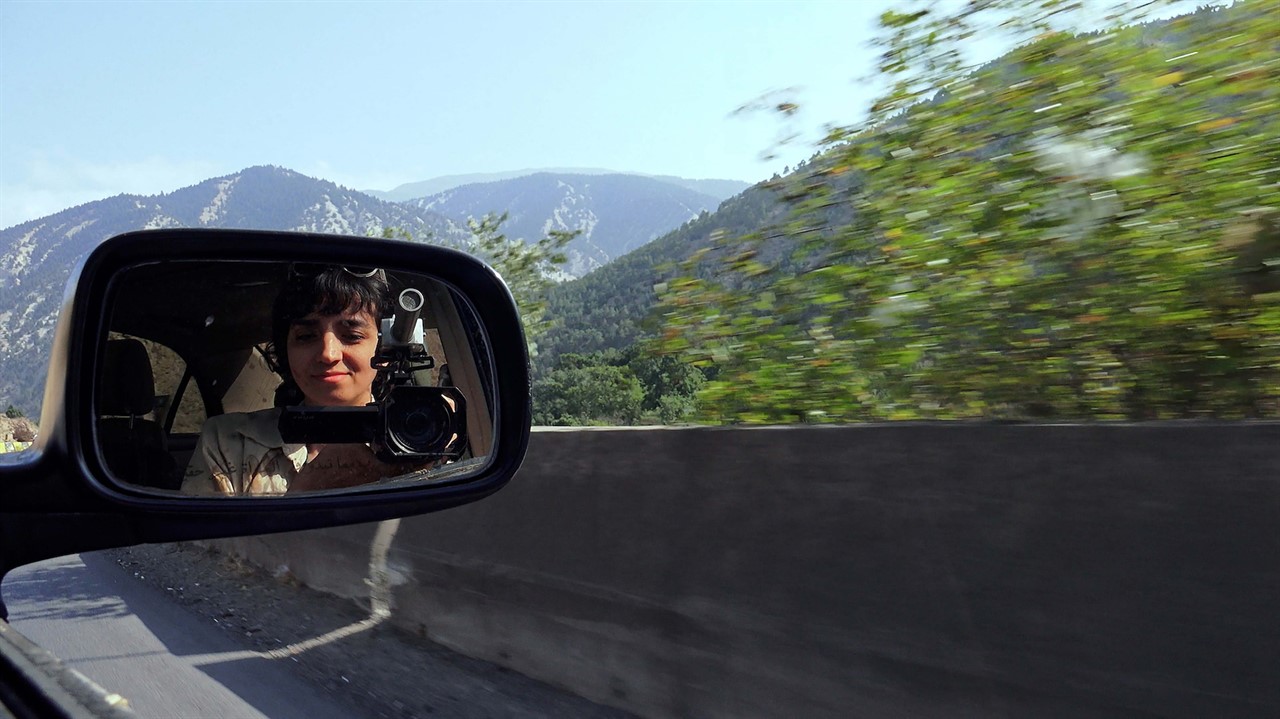 Woman with camera in car side mirror