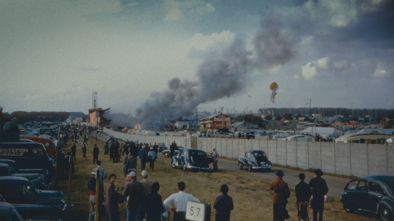 People surround cars and a plume of smoke