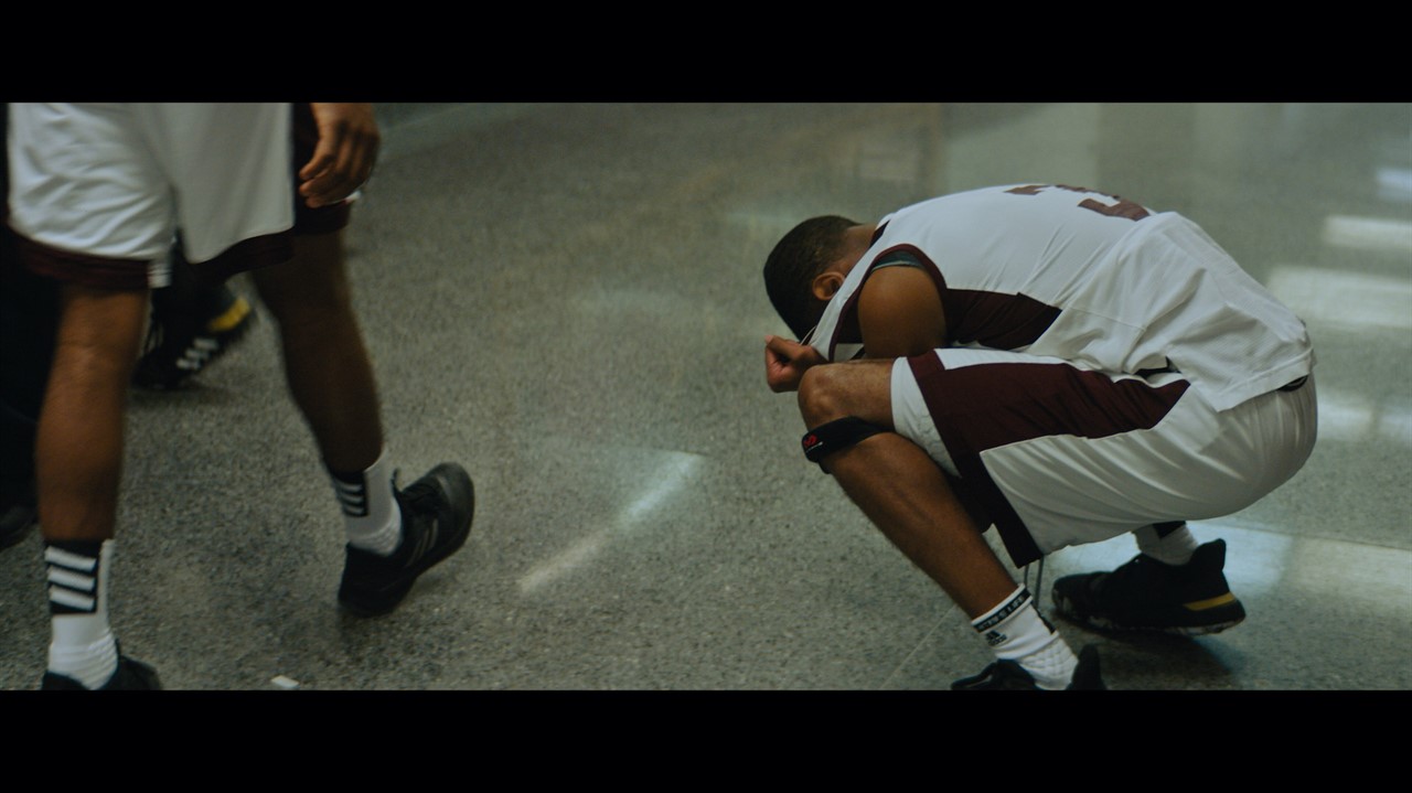 Young man in basketball uniform crouched over