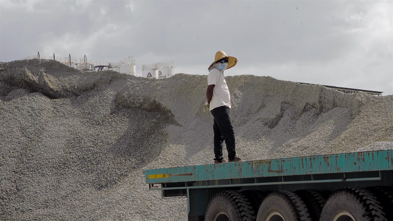 Person stands in front of a giant pile of sand