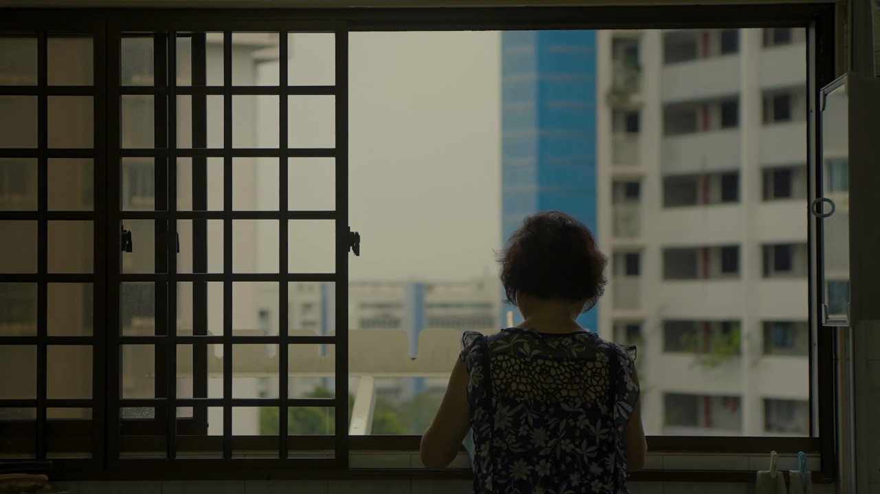 Woman looking out an open window at highrises