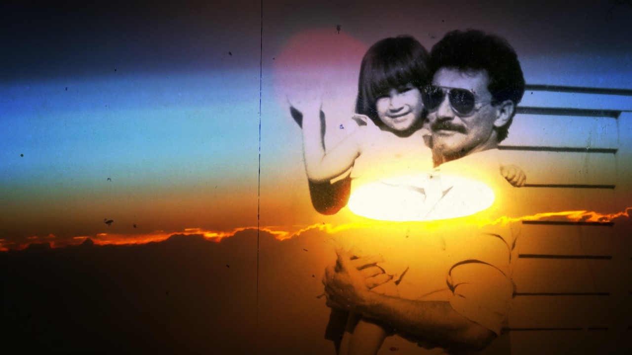 Man holding a child overlaid with a sunset