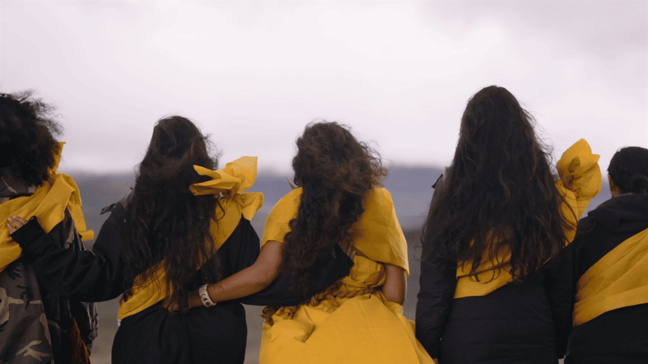 Women with arms linked wearing yellow sashes