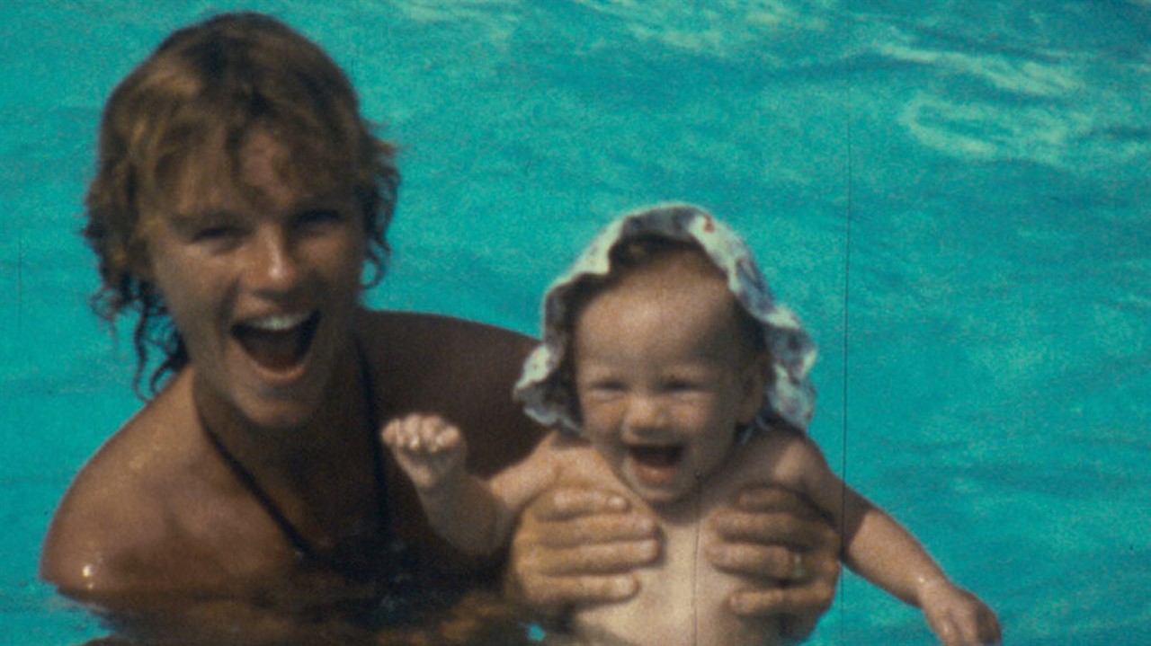Woman in a pool holding a baby