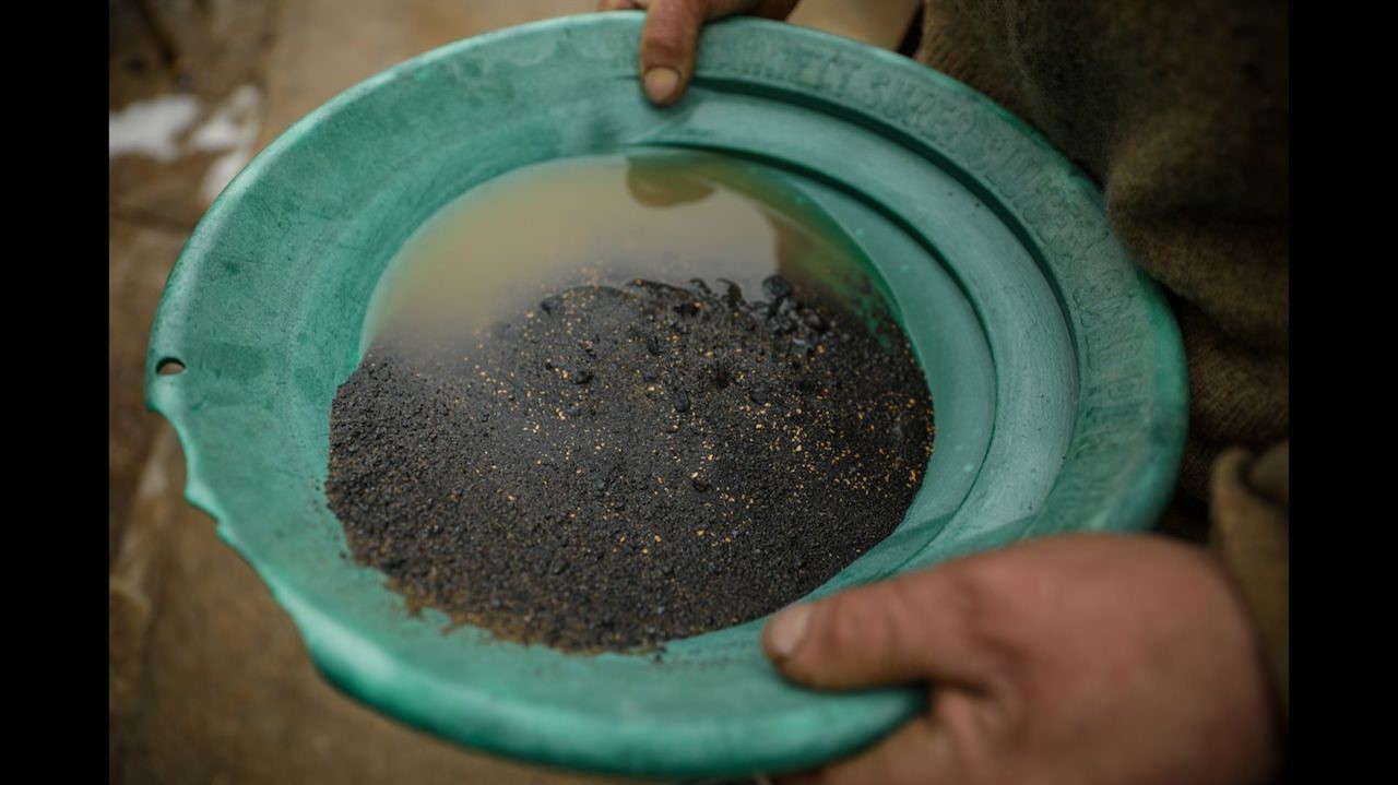 Dirt, water and specs of gold in a bowl