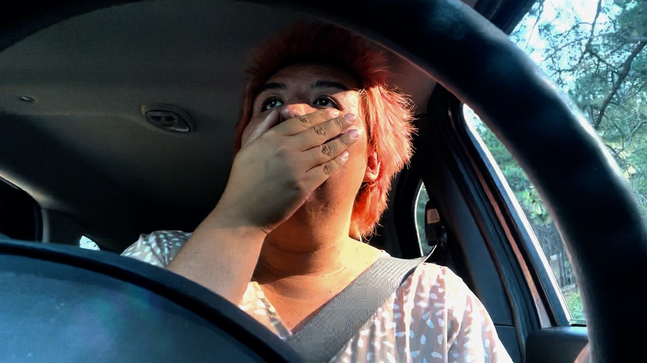 Person driving with their hand over their mouth