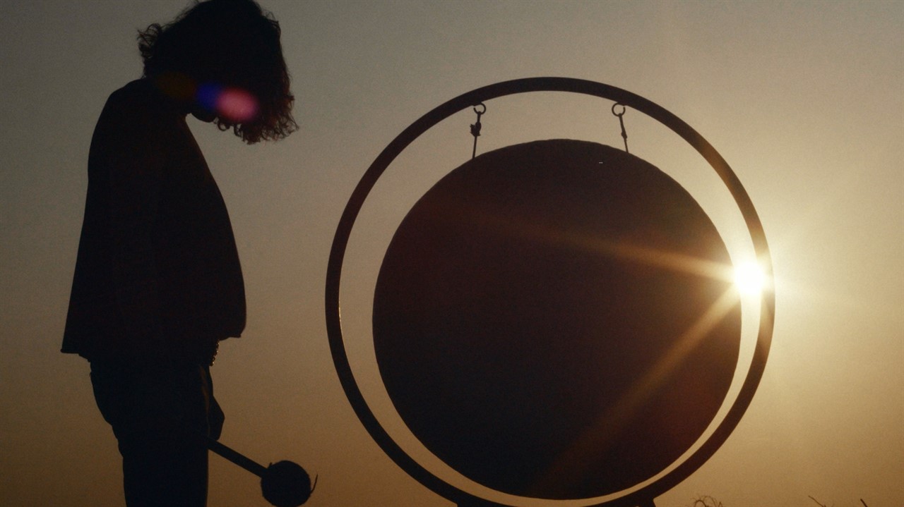 Silhouette of person beside a large gong