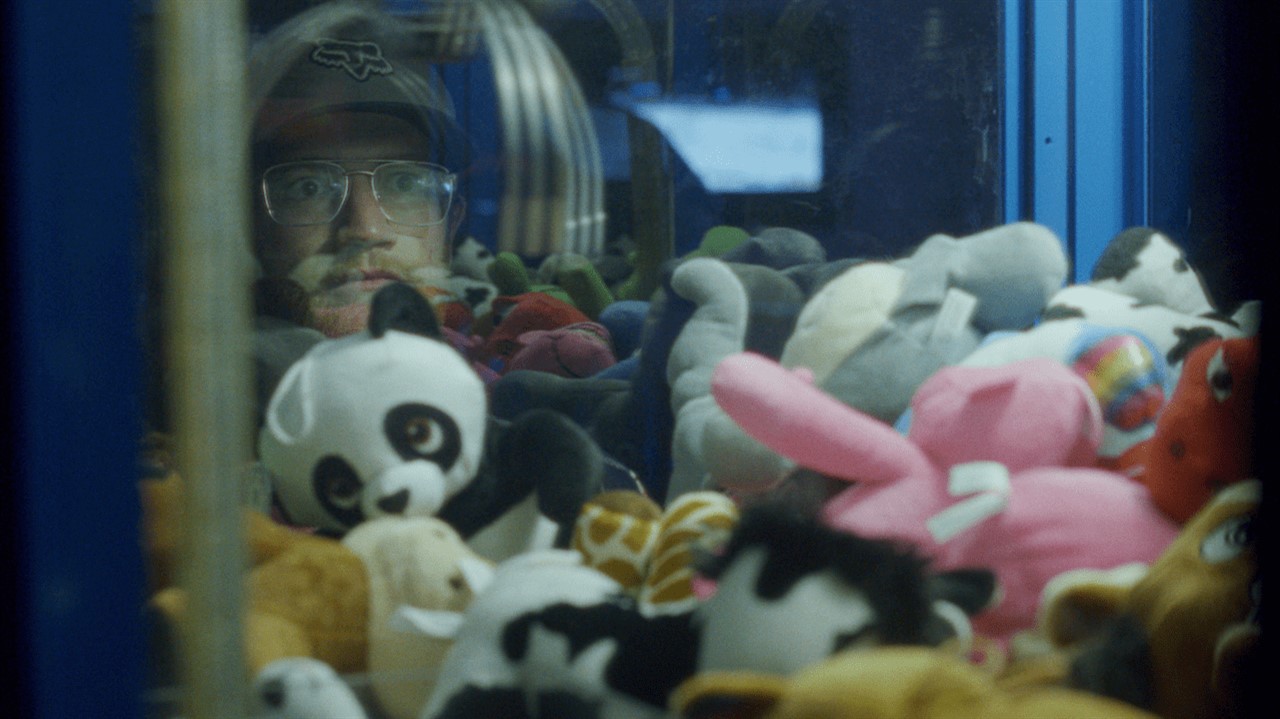 Man looking into a claw game filled with stuffies