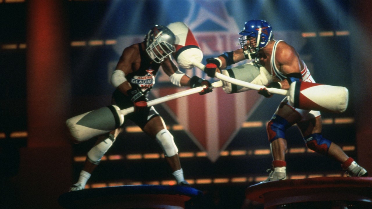 Two men in protective gear holding padded clubs