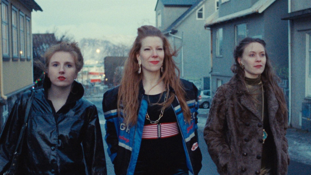 Three women walking down a street together.