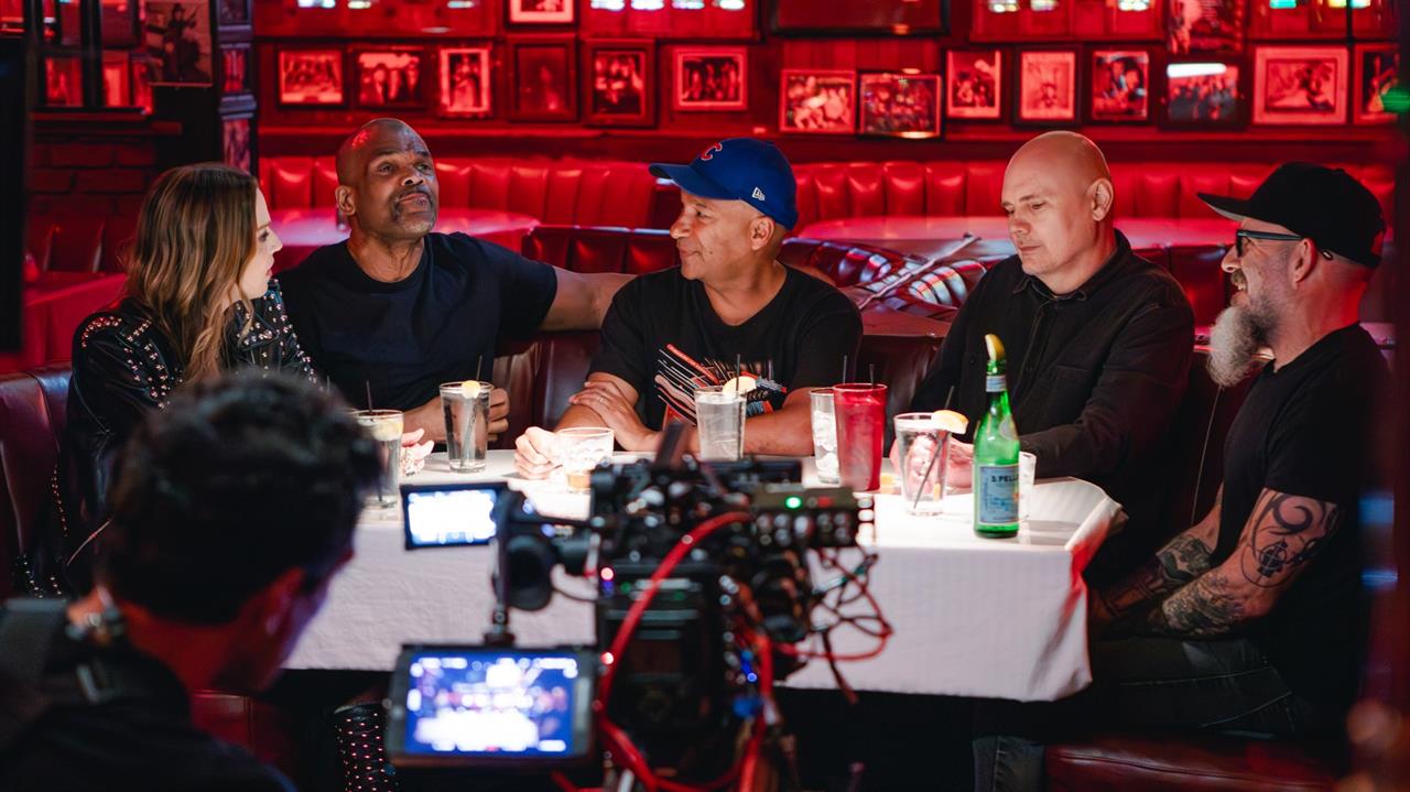 Camera filming 4 men and a woman in a restaurant