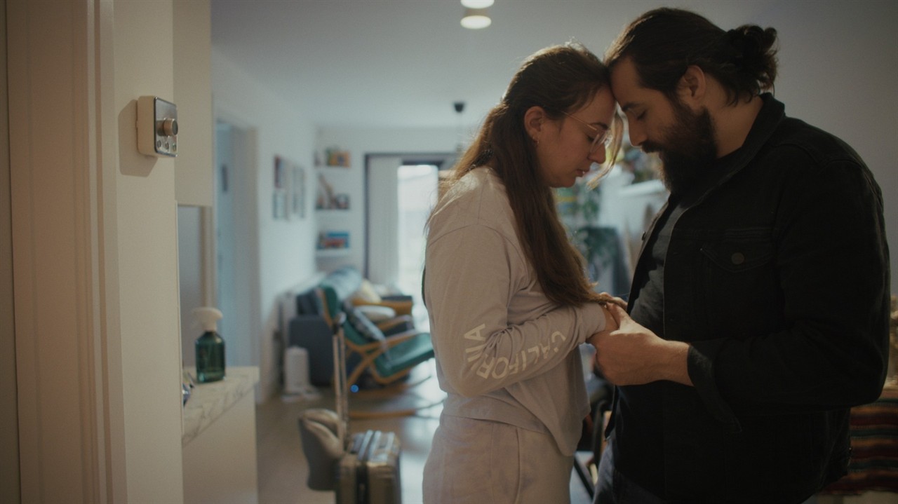 Woman and man leaning foreheads and holding hands