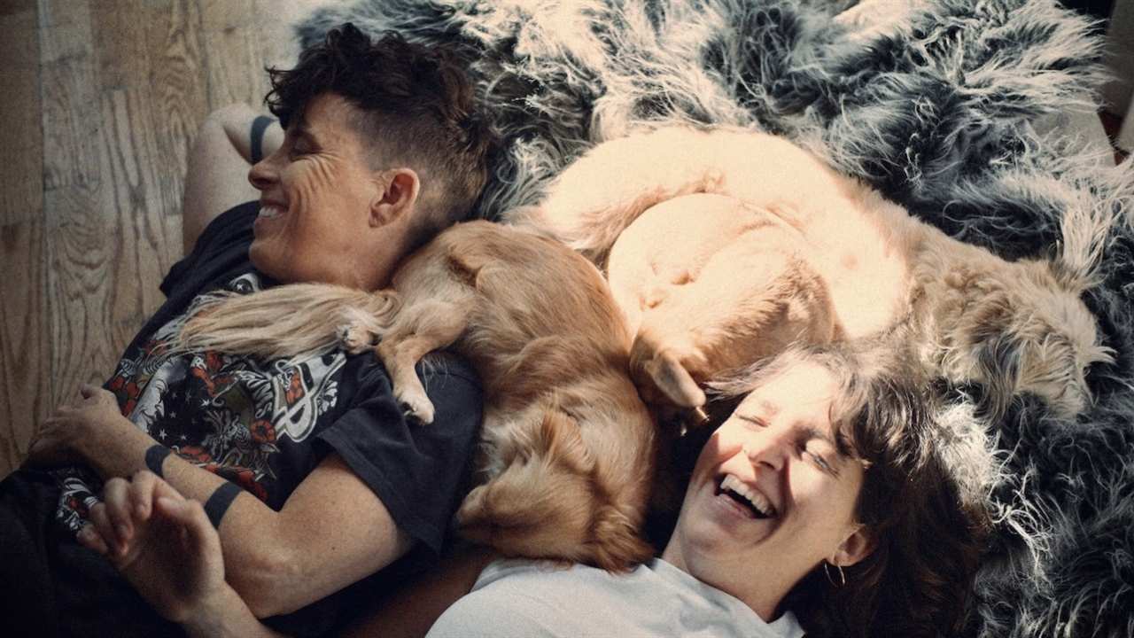 two people laying in a bed of puppies