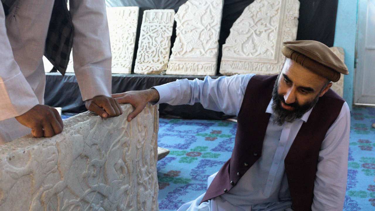 a man with a beard looking at an artifact