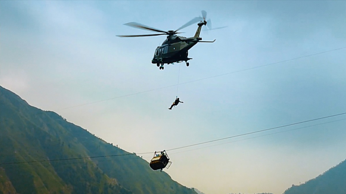 a helicopter and a person suspended over a gondola
