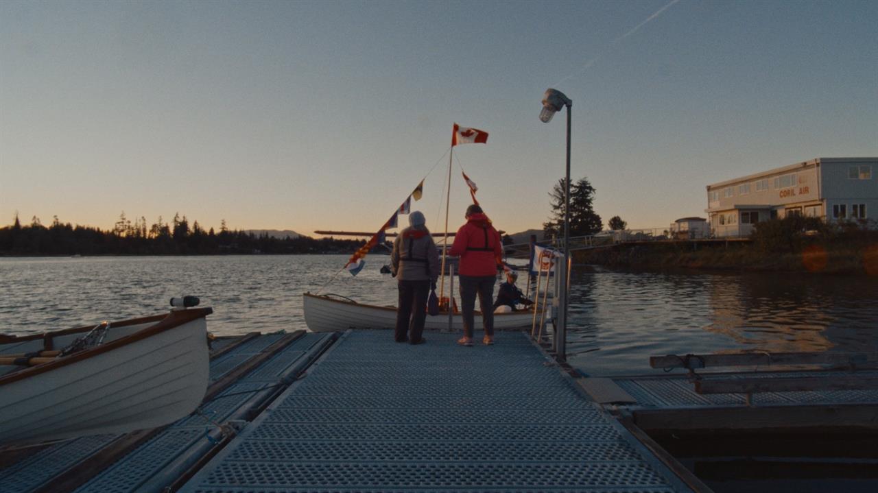 Two people stand at the end of a dock