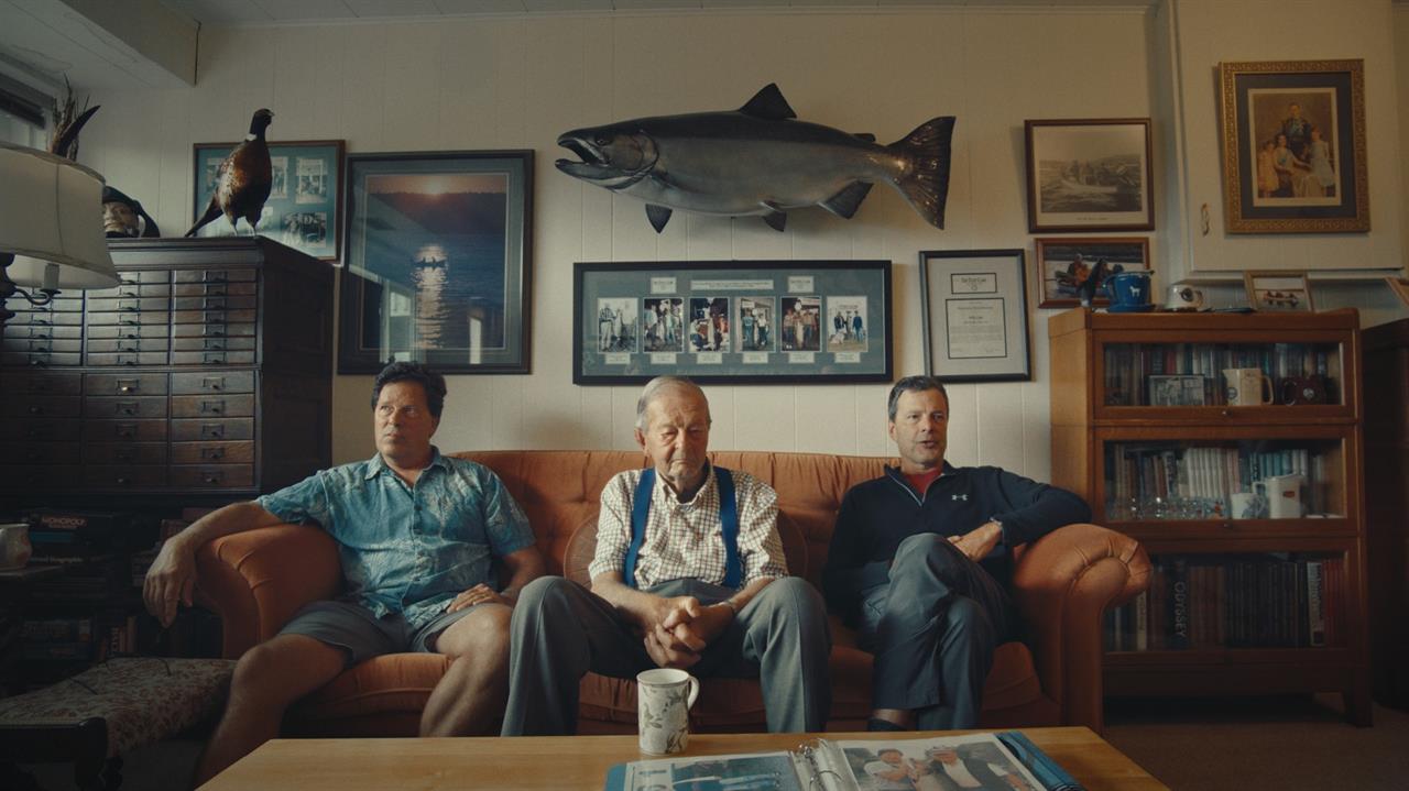 Three men of varying ages sit on a couch