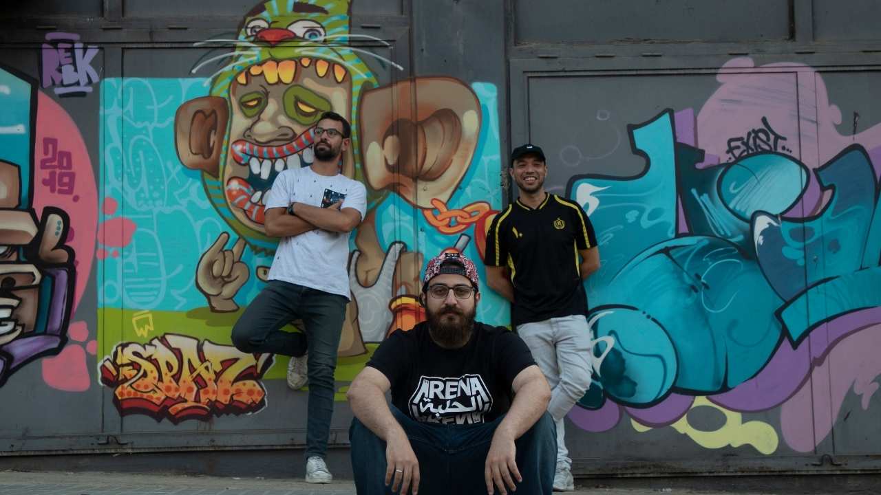 three men in front of a mural