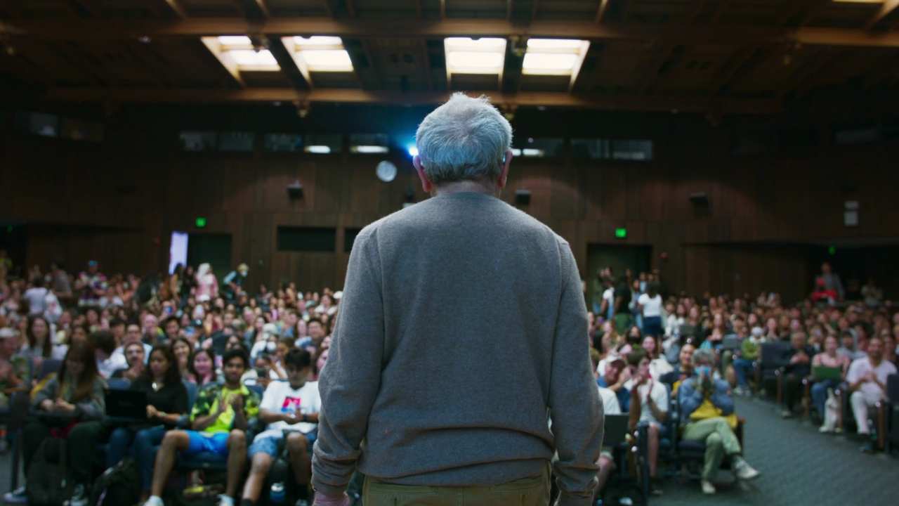 a man speaking to a large group of students
