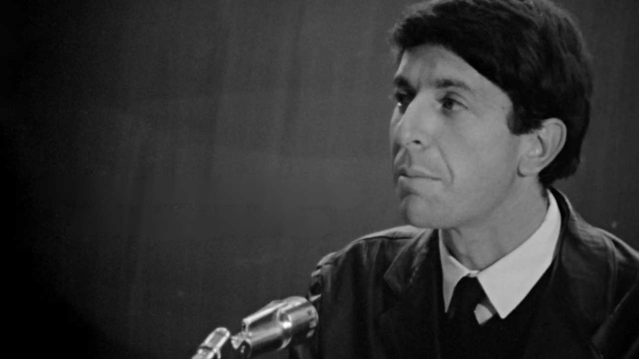 Leonard Cohen in a suit on front of a microphone