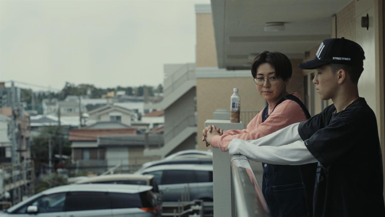 Two people stand on an apartment balcony