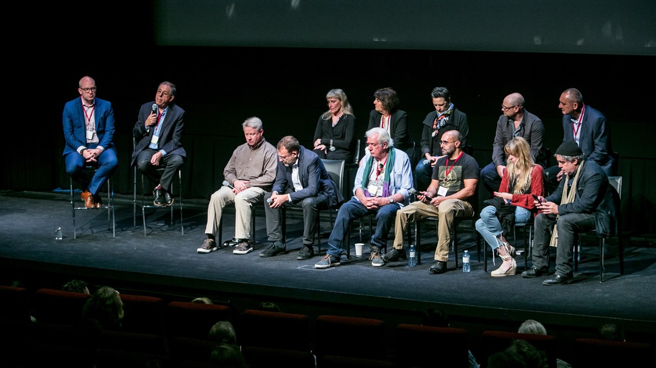 Group of serious-looking people sit on stage