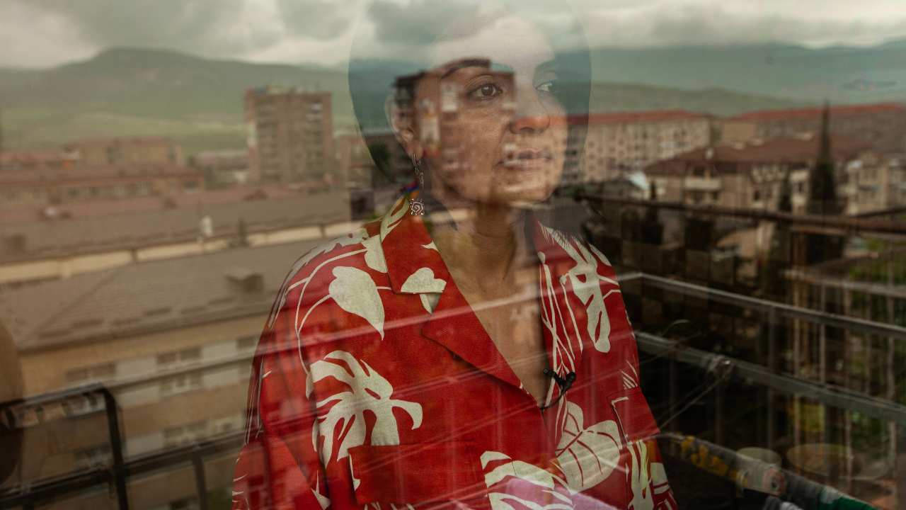 a woman in a red print top looking out a window