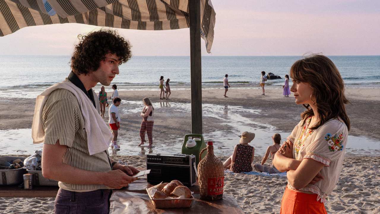 a young man and woman talking at the beach