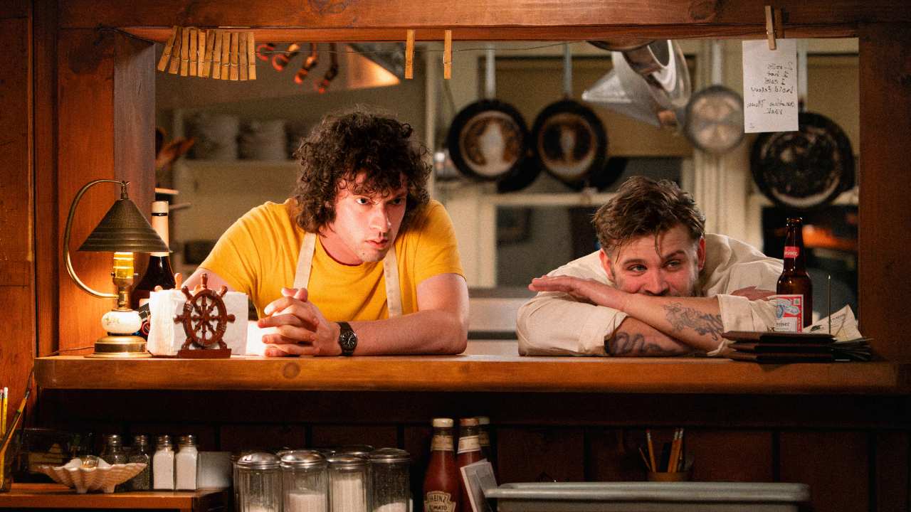 two men leaning on a counter in a restaurant