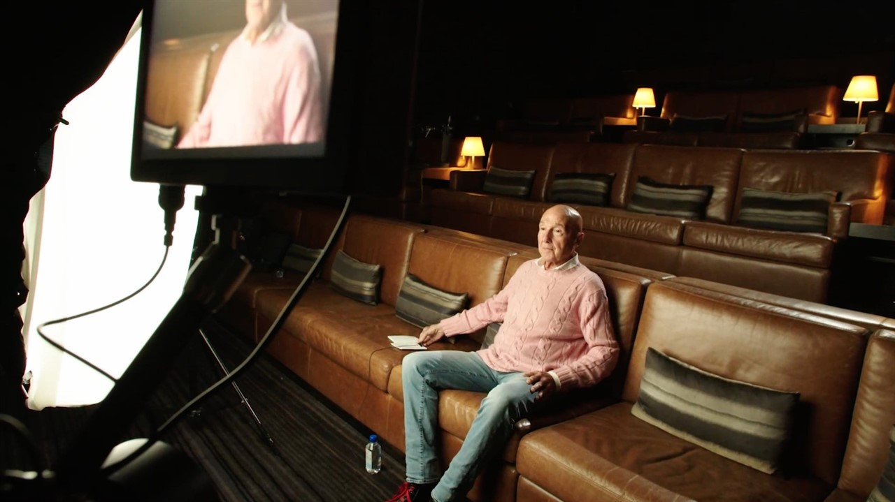 Older man sitting on film set on leather bench