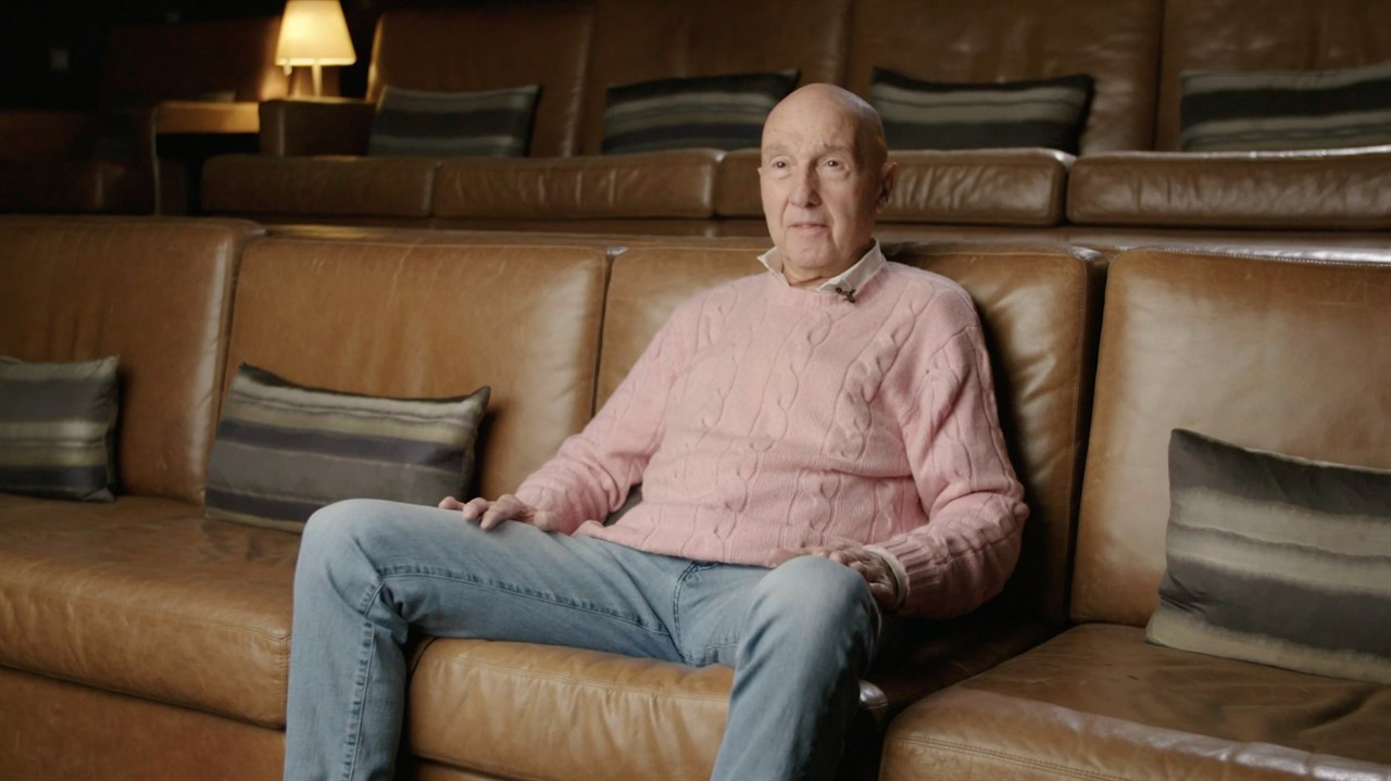 Older white man sitting on leather bench