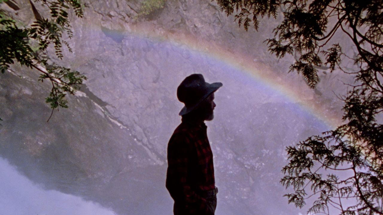 a man with a bucket hat by a rainbow
