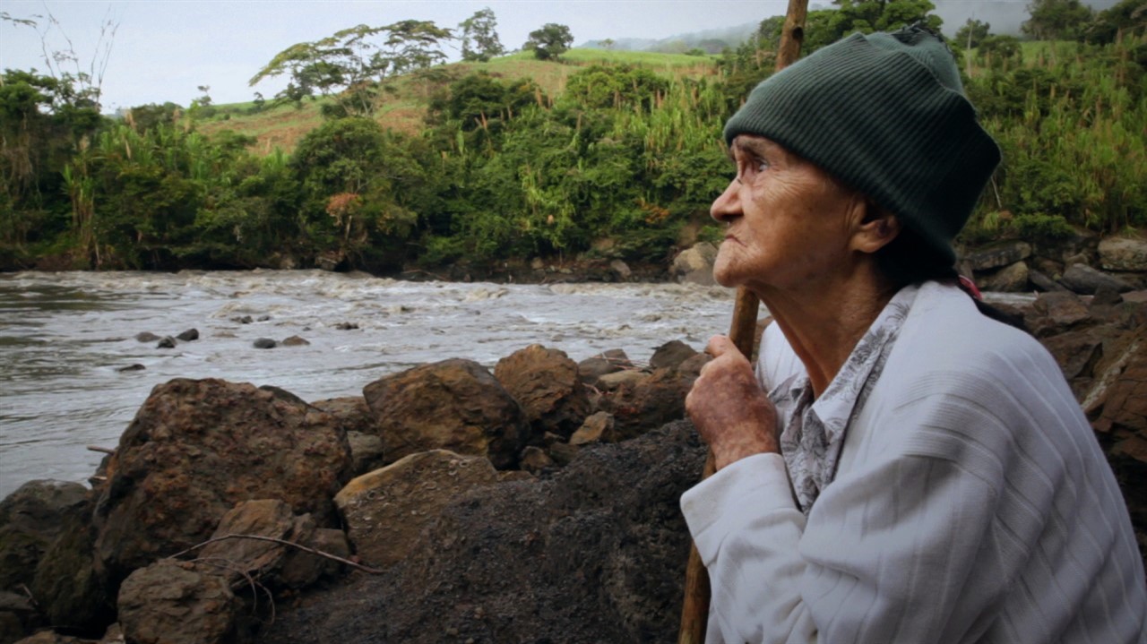 An elderly woman looks out over a river