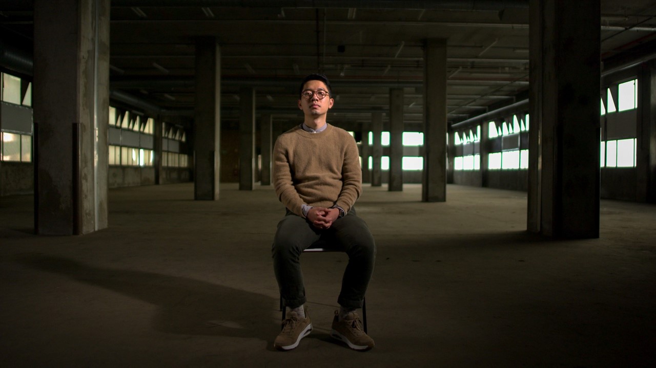 Nathan Law sitting in an empty warehouse