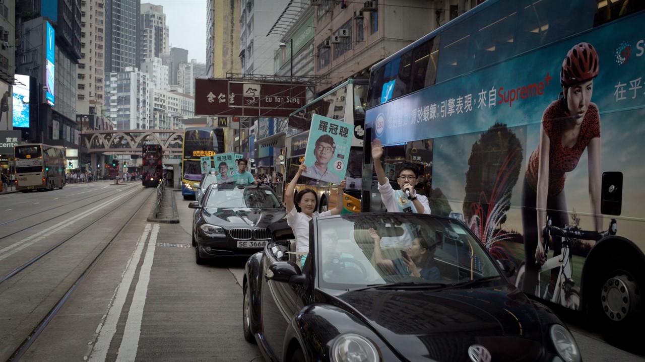 Nathan Law in a car with people holding signs with